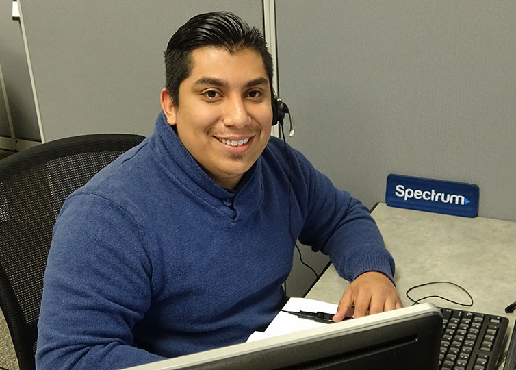 Male Spectrum Call Center Representative in a blue sweater wearing a telephone headset
